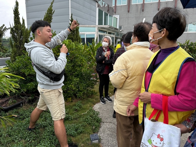 導覽人員在戶外植物區向遊客介紹月桃