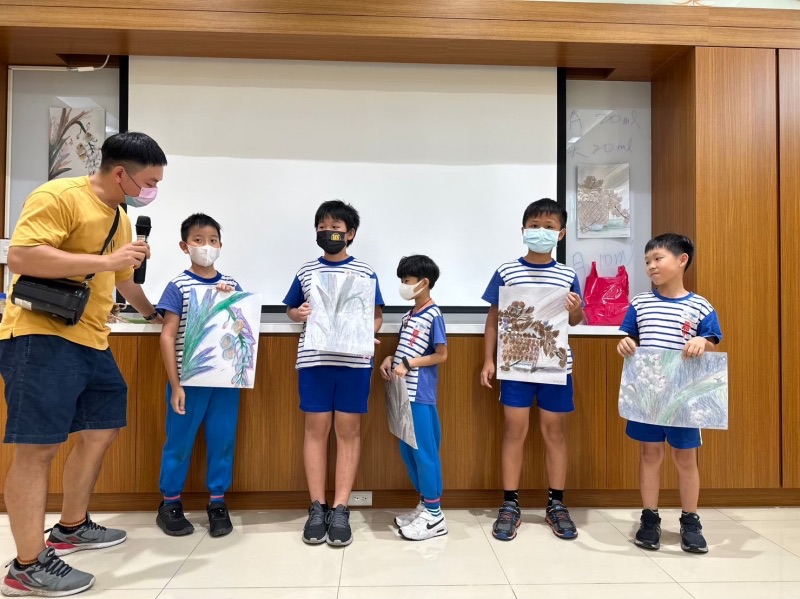 學生舉起完成的作品，與導覽老師合影